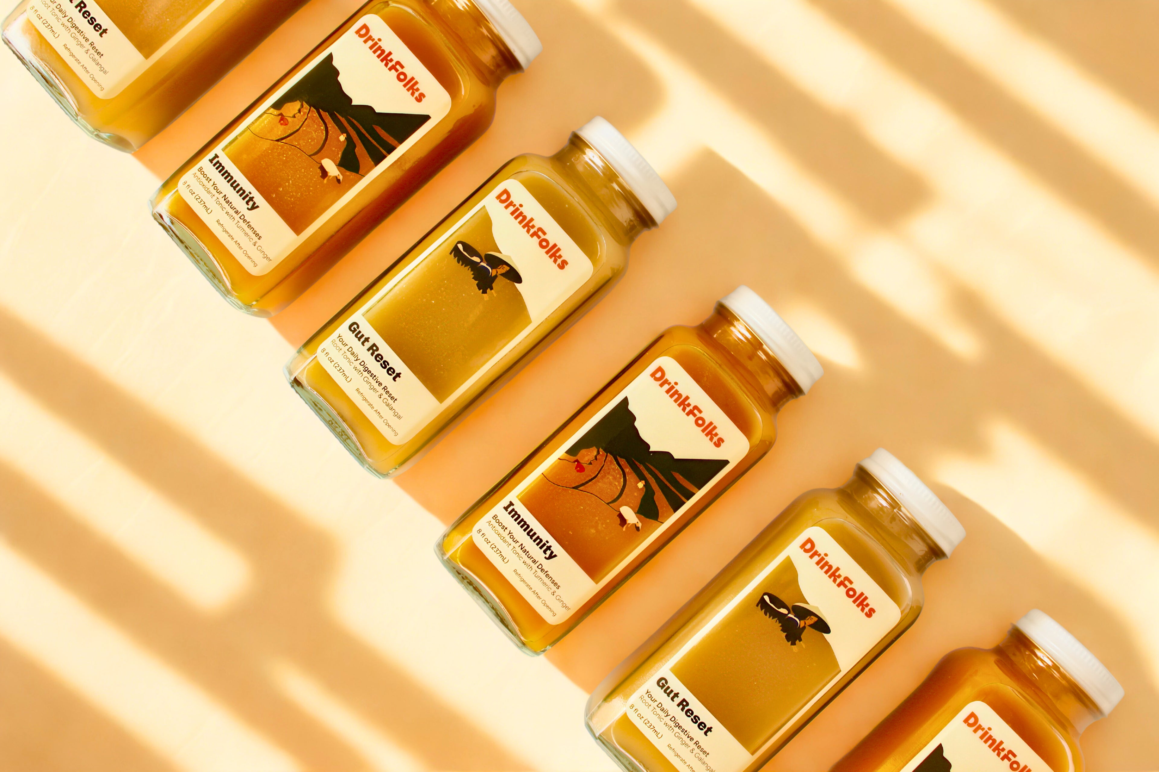six bottles of 'DrinkFolks' jamu (featuring immunity and gut recovery) on a beige background
